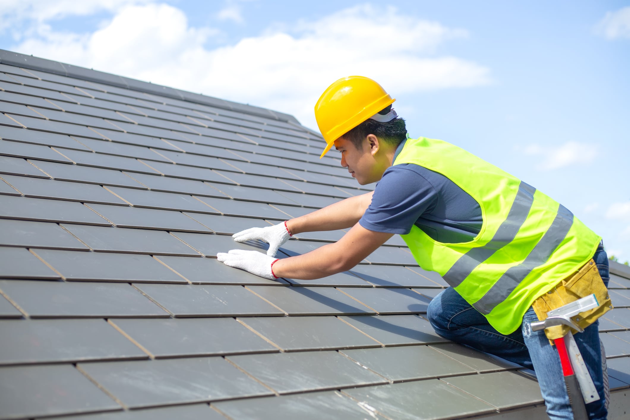 Builder Working On Roof Of New Building, Construction worker wearing safety harness and safety line working on roof new warehouse.