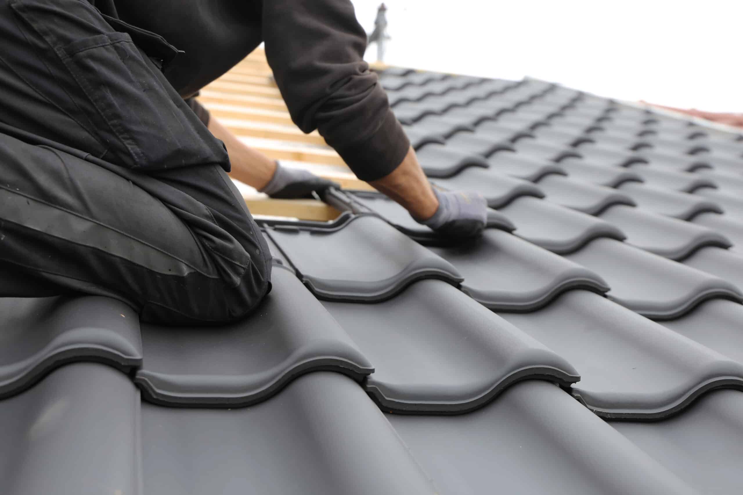 worker on roof putting shingles down