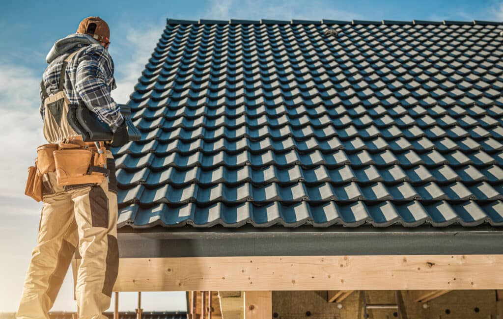 Tile Roofing Worker and the House Construction. Scaffolding on the Home Side. Industrial Theme.